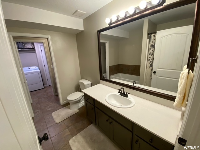 Bathroom with toilet, a bathtub, tile floors, large vanity, and washer / clothes dryer