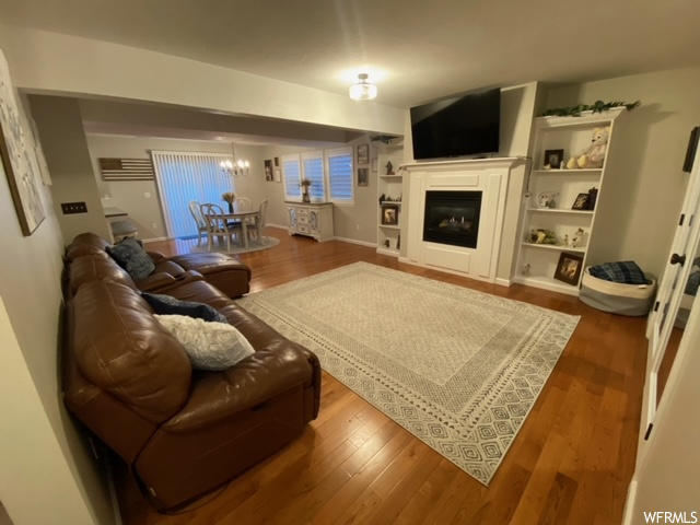 Living room with hardwood / wood-style floors, built in features, and a fireplace