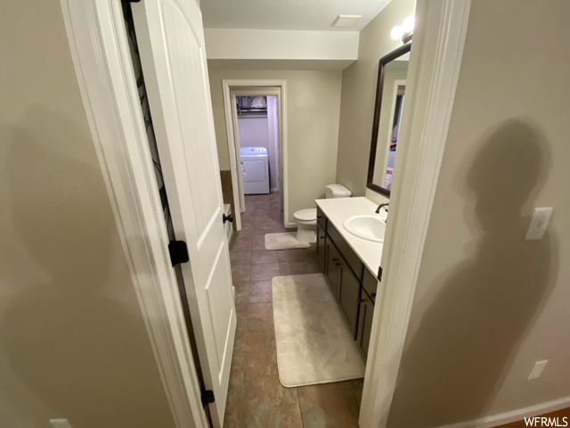 Bathroom featuring tile floors, large vanity, washer / dryer, and toilet