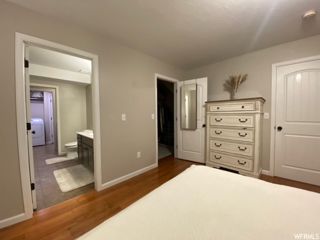 Tiled bedroom featuring a closet, ensuite bathroom, a walk in closet, and washer / clothes dryer