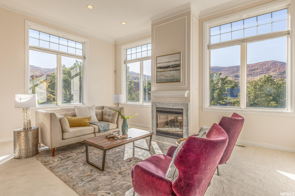 Living room with light carpet, a fireplace, a mountain view, and ornamental molding
