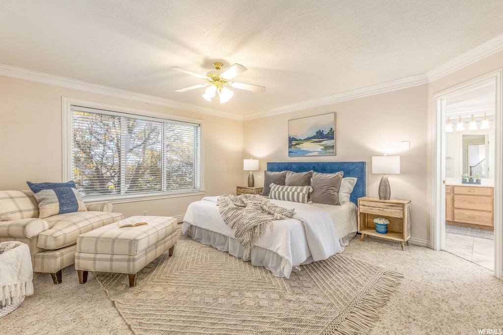 Carpeted bedroom with connected bathroom, crown molding, and ceiling fan