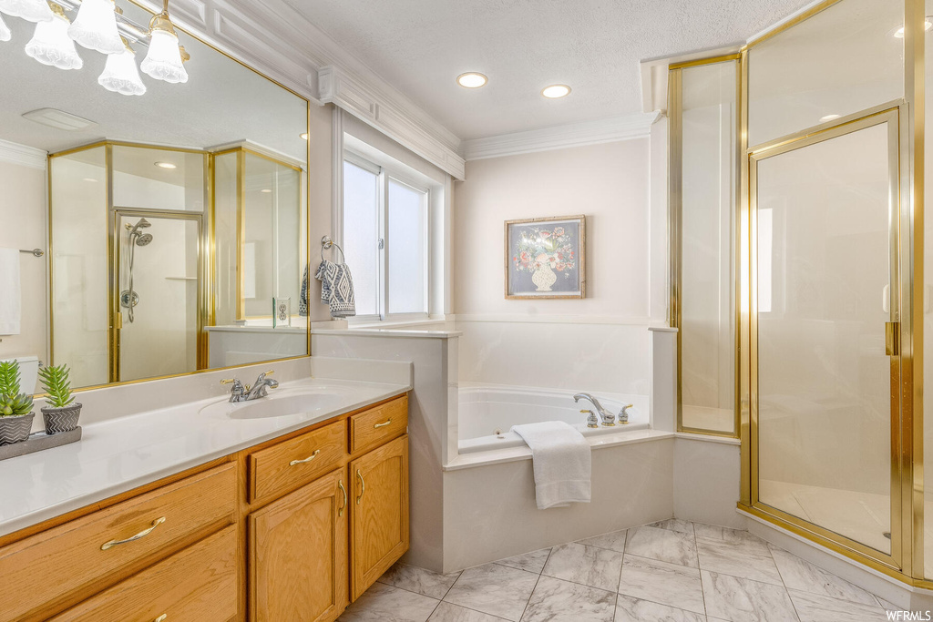 Bathroom featuring tile floors, large vanity, a textured ceiling, shower with separate bathtub, and ornamental molding