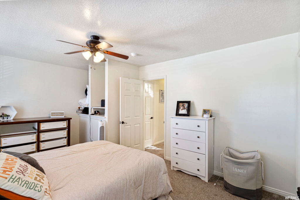 Carpeted bedroom with ceiling fan and a textured ceiling