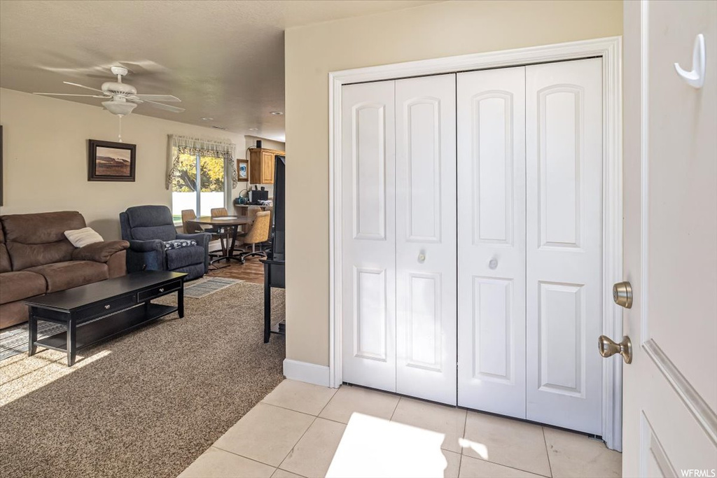 Living room with ceiling fan and light tile floors