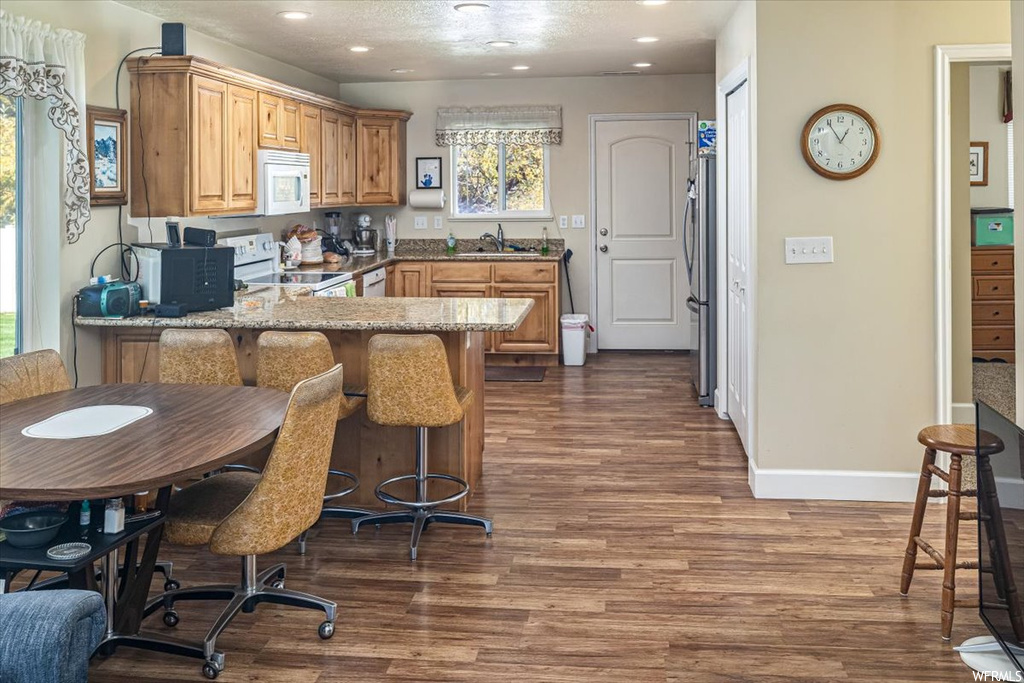 Kitchen featuring a healthy amount of sunlight, sink, light stone countertops, and dark hardwood / wood-style floors