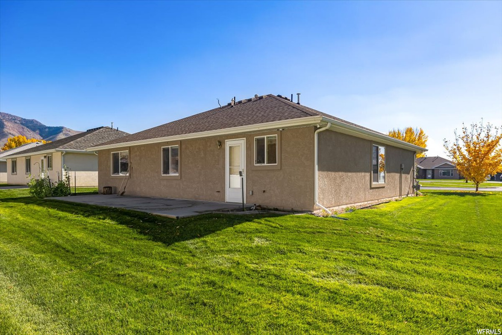 Back of house with a yard and a patio