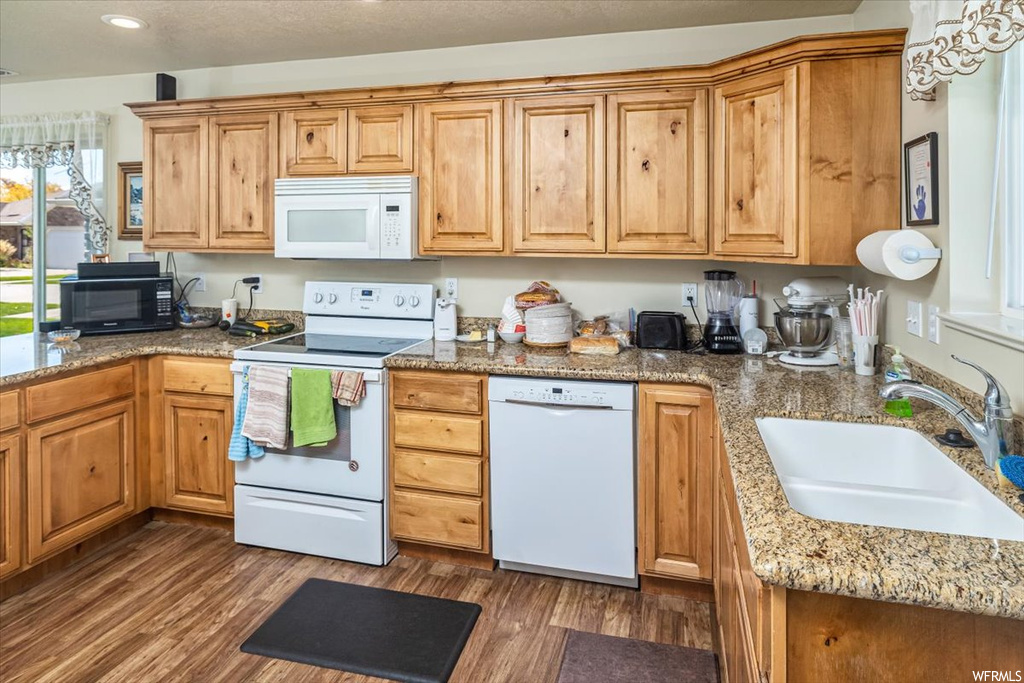 Kitchen featuring dark hardwood / wood-style flooring, white appliances, sink, and dark stone counters