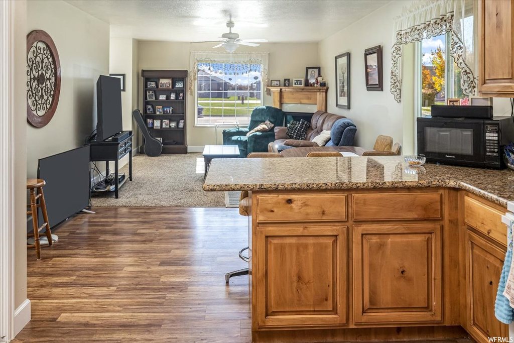 Kitchen featuring dark hardwood / wood-style flooring, ceiling fan, and light stone countertops