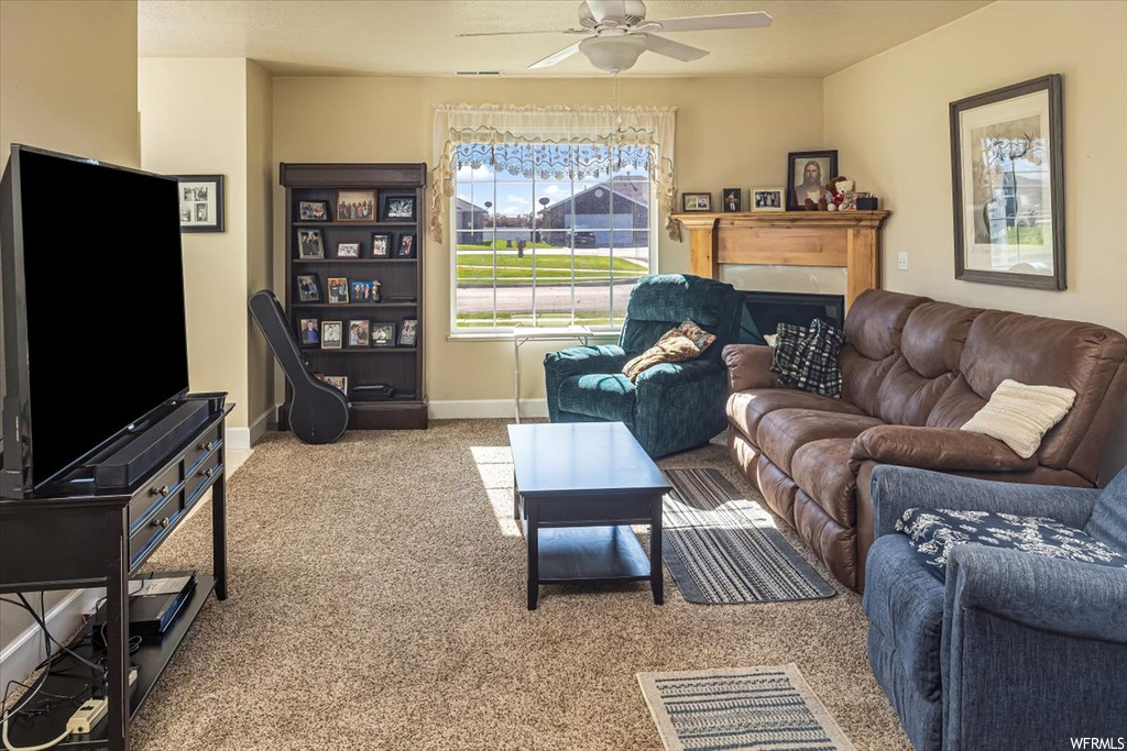 Living room with ceiling fan, light carpet, and a fireplace