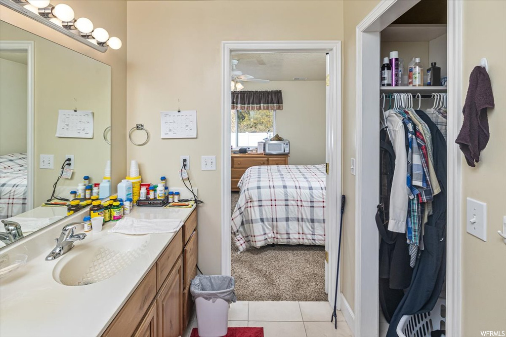 Bathroom with vanity with extensive cabinet space, ceiling fan, and tile flooring