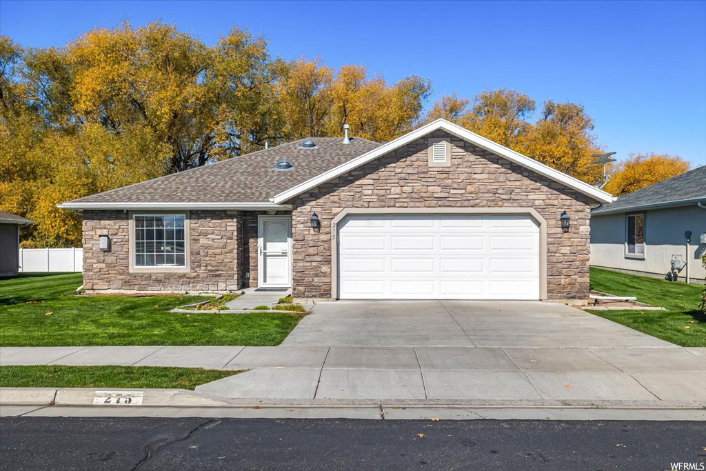 Ranch-style home featuring a garage and a front lawn