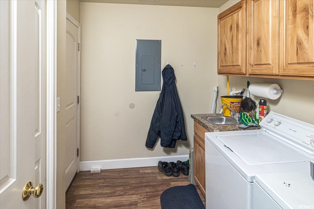 Clothes washing area with dark hardwood / wood-style flooring, cabinets, separate washer and dryer, and sink