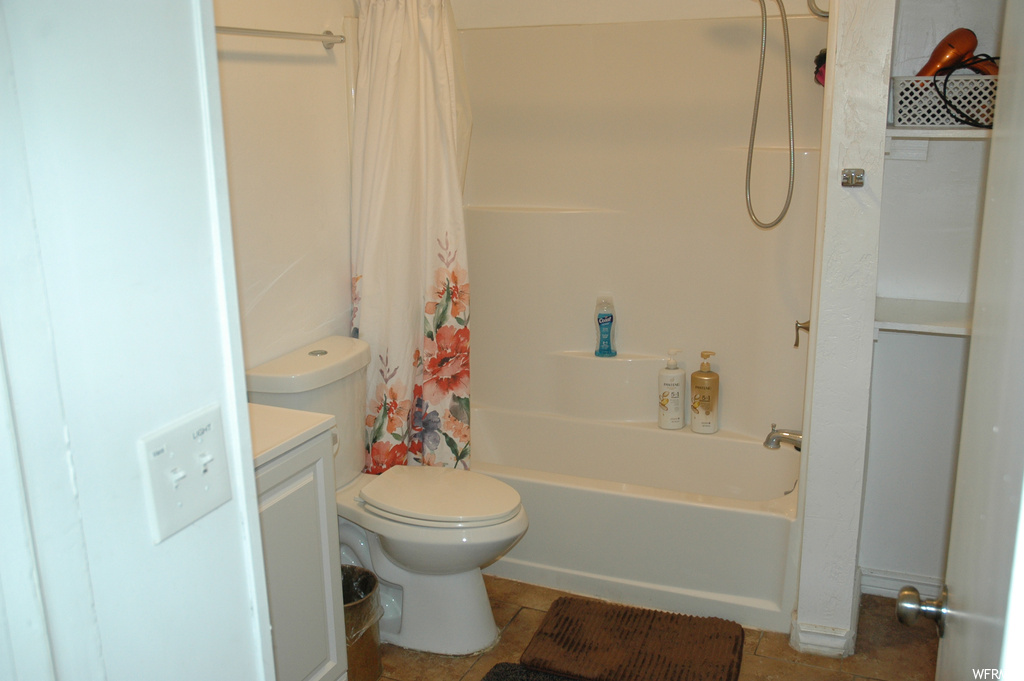 Full bathroom featuring tile floors, toilet, vanity, and shower / bath combo