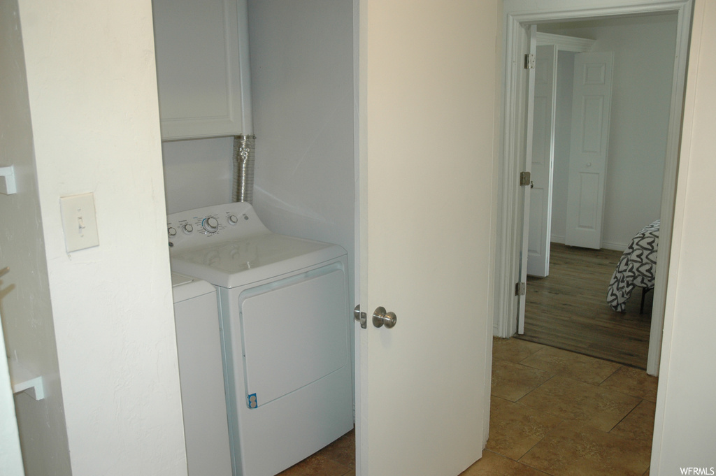 Laundry room with light wood-type flooring and washing machine and clothes dryer