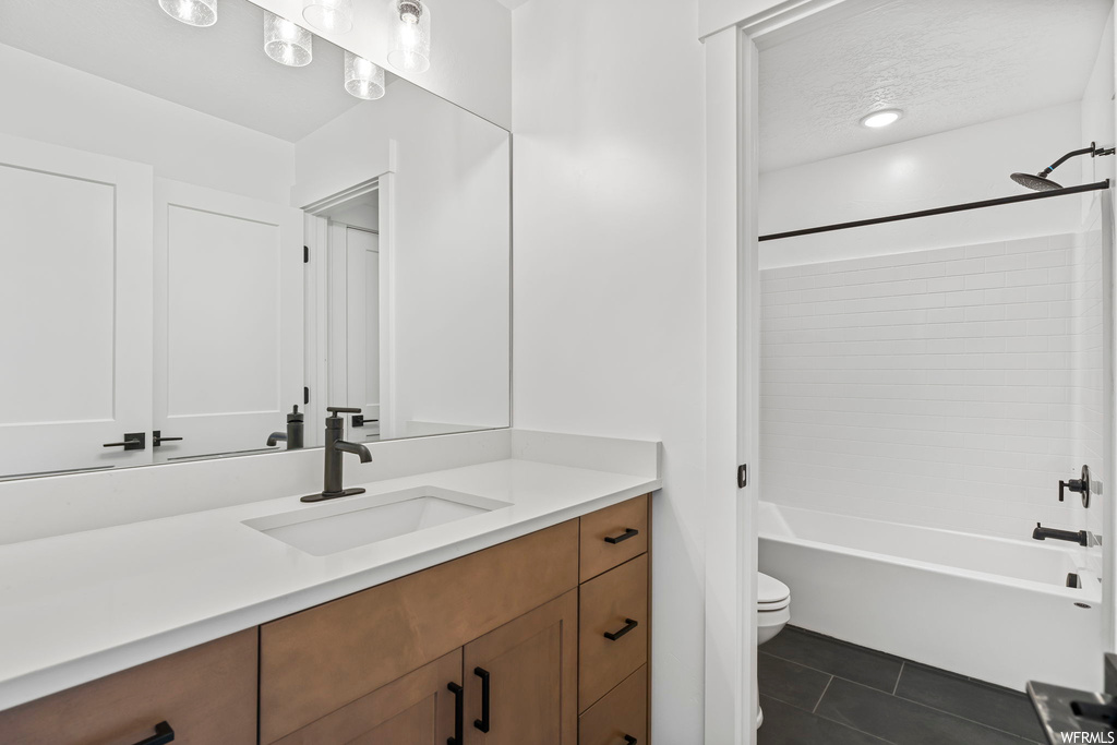 Full bathroom featuring shower / bath combination, tile floors, toilet, and vanity with extensive cabinet space