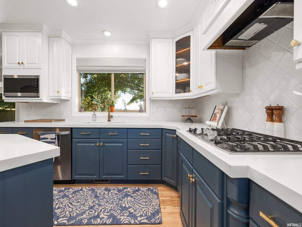 Kitchen featuring backsplash, wall chimney exhaust hood, and white cabinetry