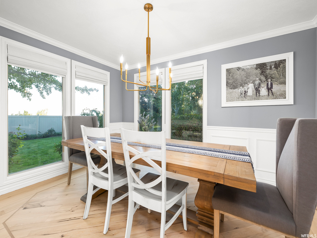 Dining space featuring light parquet flooring, a notable chandelier, and ornamental molding