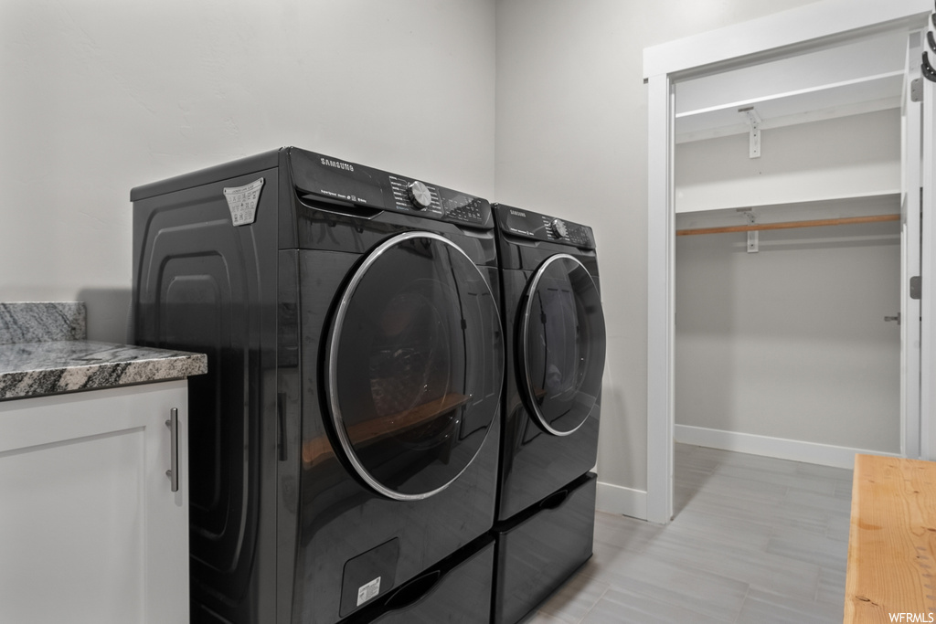 Laundry area featuring cabinets, washing machine and clothes dryer, and light hardwood / wood-style flooring