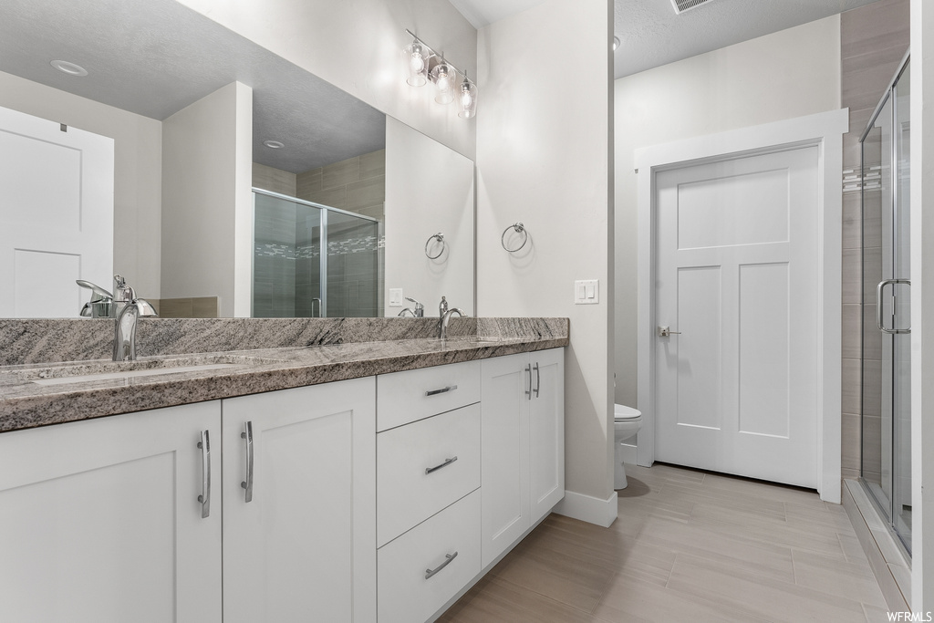 Bathroom with vanity with extensive cabinet space, toilet, and dual sinks