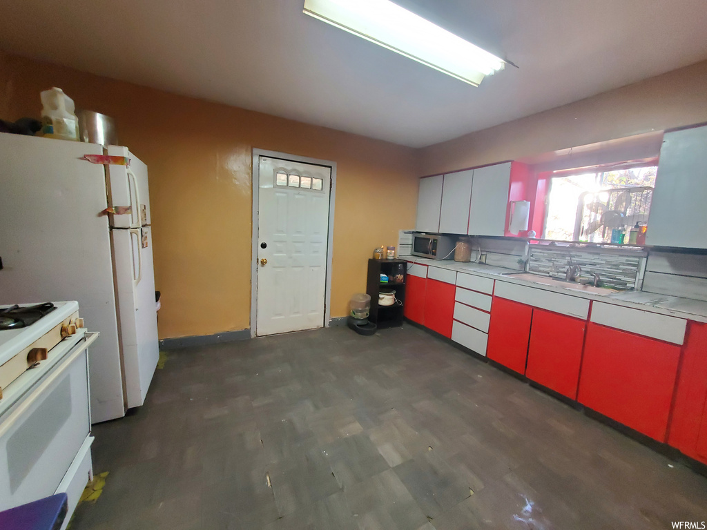 Kitchen featuring backsplash, dark hardwood / wood-style flooring, and white range with gas cooktop