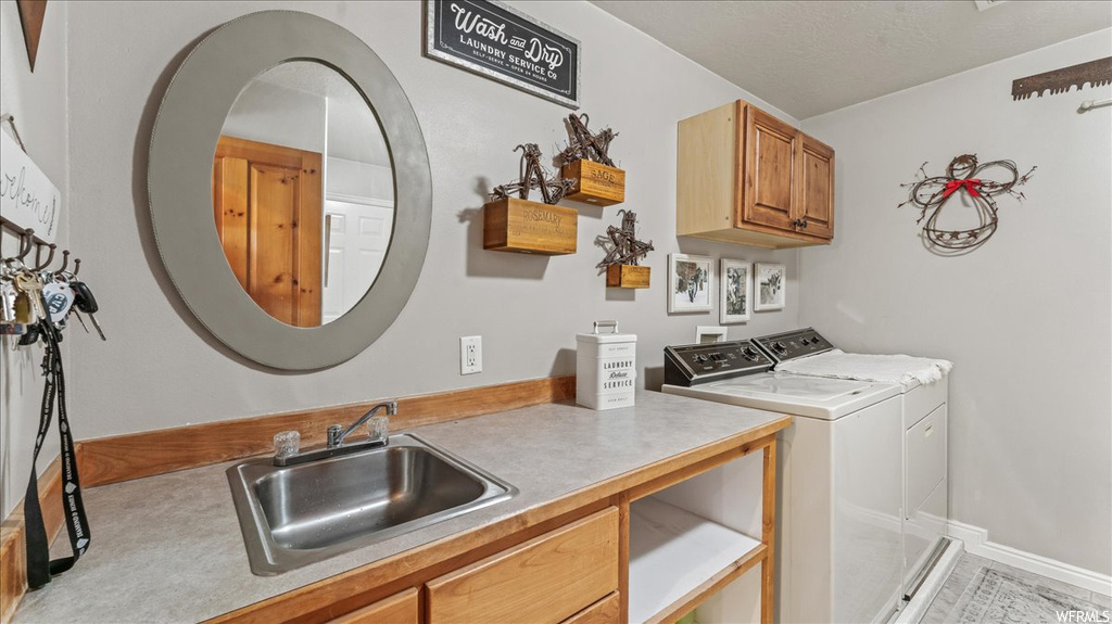 Laundry area featuring cabinets, light tile flooring, separate washer and dryer, and sink