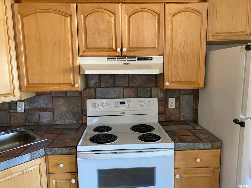 Kitchen featuring white appliances, backsplash, and sink