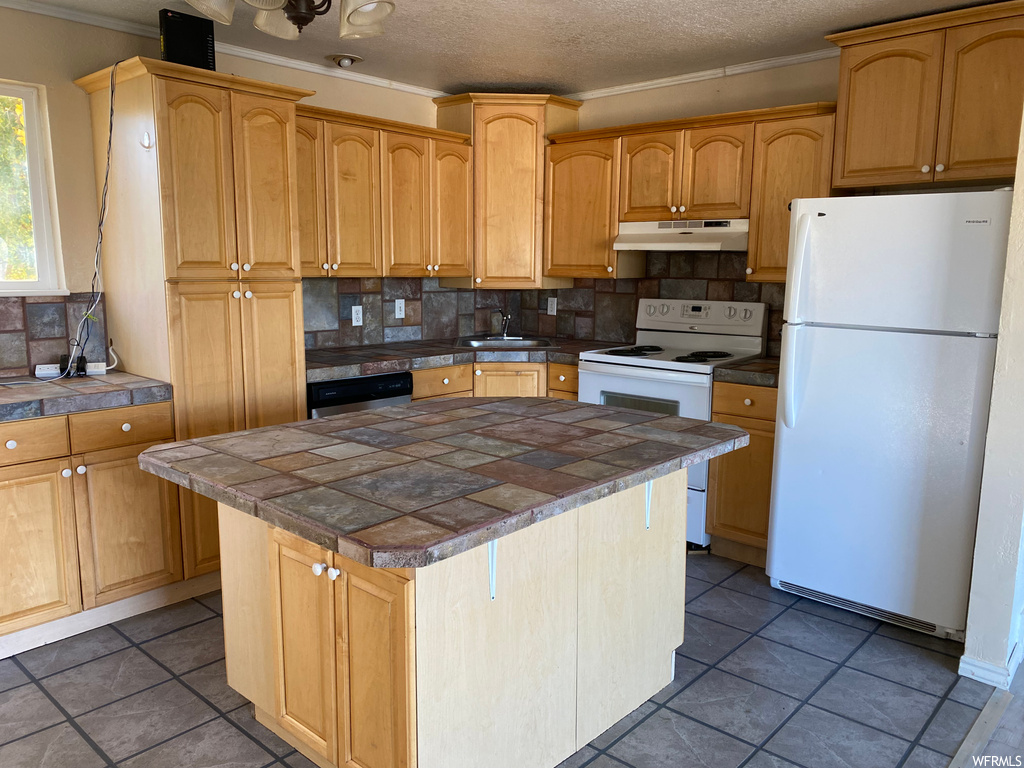 Kitchen with white appliances, tasteful backsplash, tile countertops, and dark tile flooring