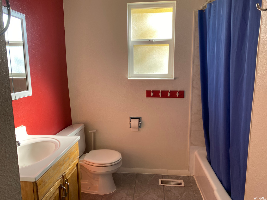 Full bathroom with plenty of natural light, large vanity, toilet, and tile flooring
