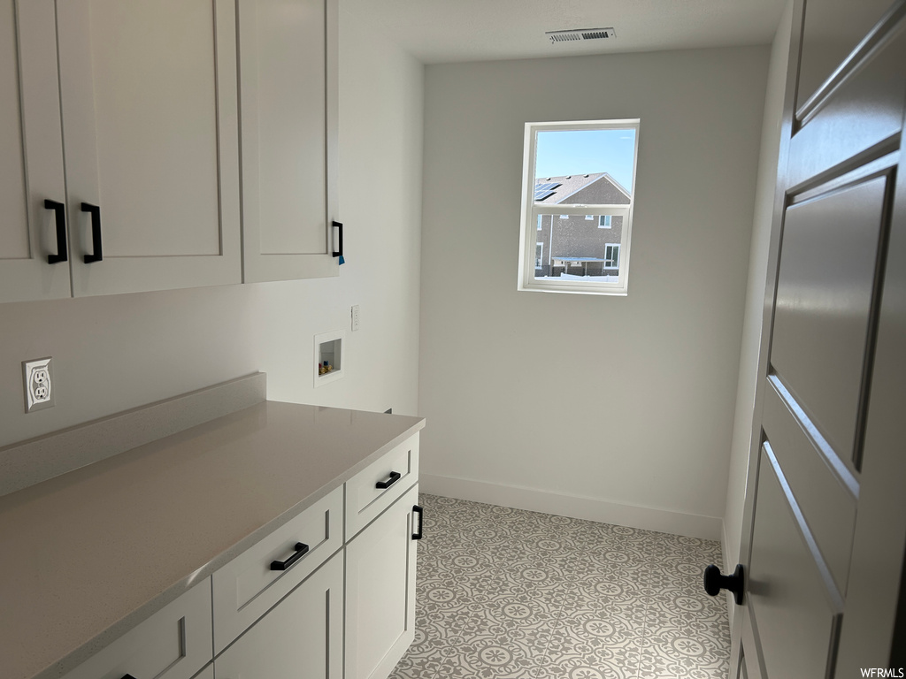 Washroom with cabinets, light tile floors, and hookup for a washing machine