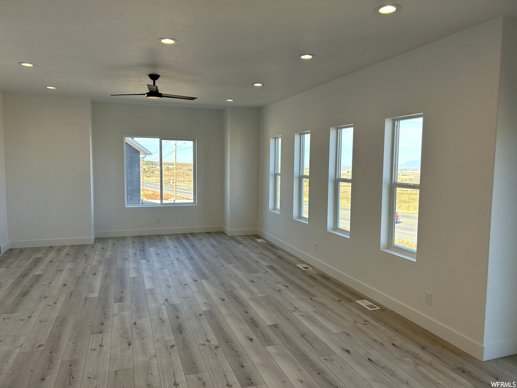 Spare room featuring light hardwood / wood-style floors, a wealth of natural light, and ceiling fan
