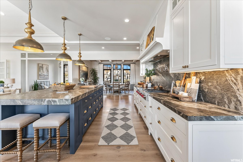 Kitchen with decorative light fixtures, tasteful backsplash, blue cabinets, and white cabinets
