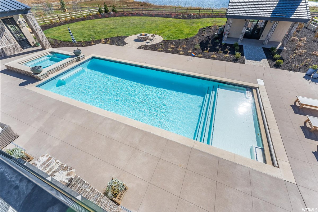 View of pool featuring an in ground hot tub, a lawn, and a patio