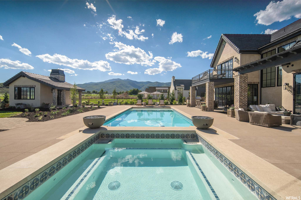 View of swimming pool featuring a mountain view, a patio area, and an in ground hot tub