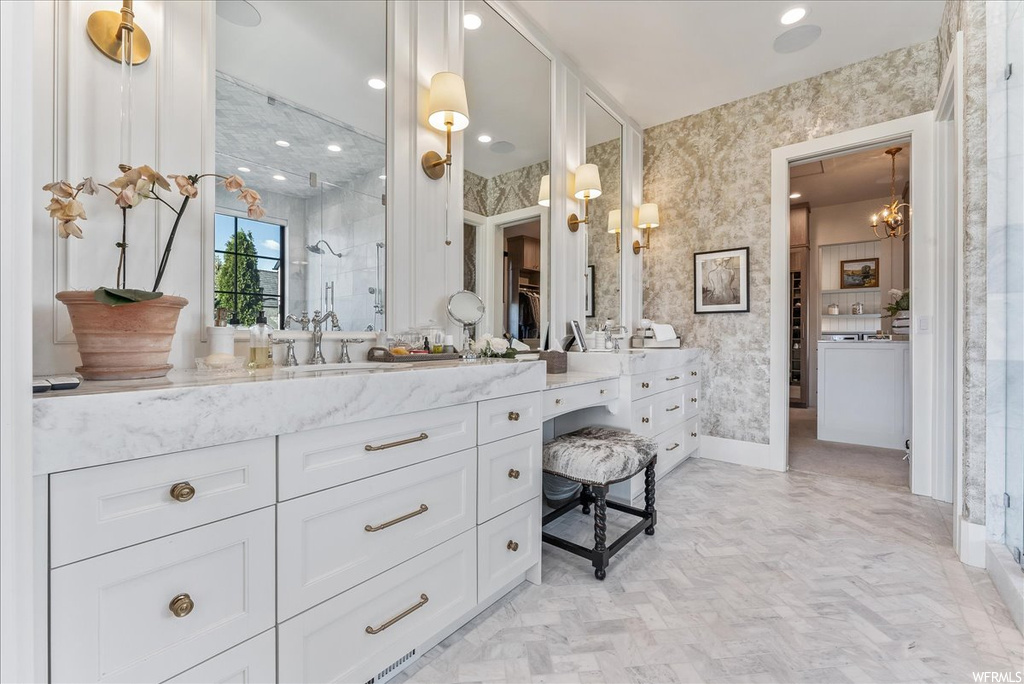 Bathroom with oversized vanity, an inviting chandelier, a shower, and tile flooring