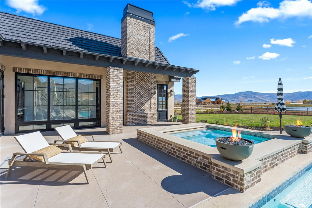 View of swimming pool with a mountain view, a patio area, and an in ground hot tub