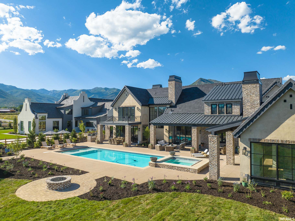 View of swimming pool with a mountain view, a patio area, an in ground hot tub, and a fire pit
