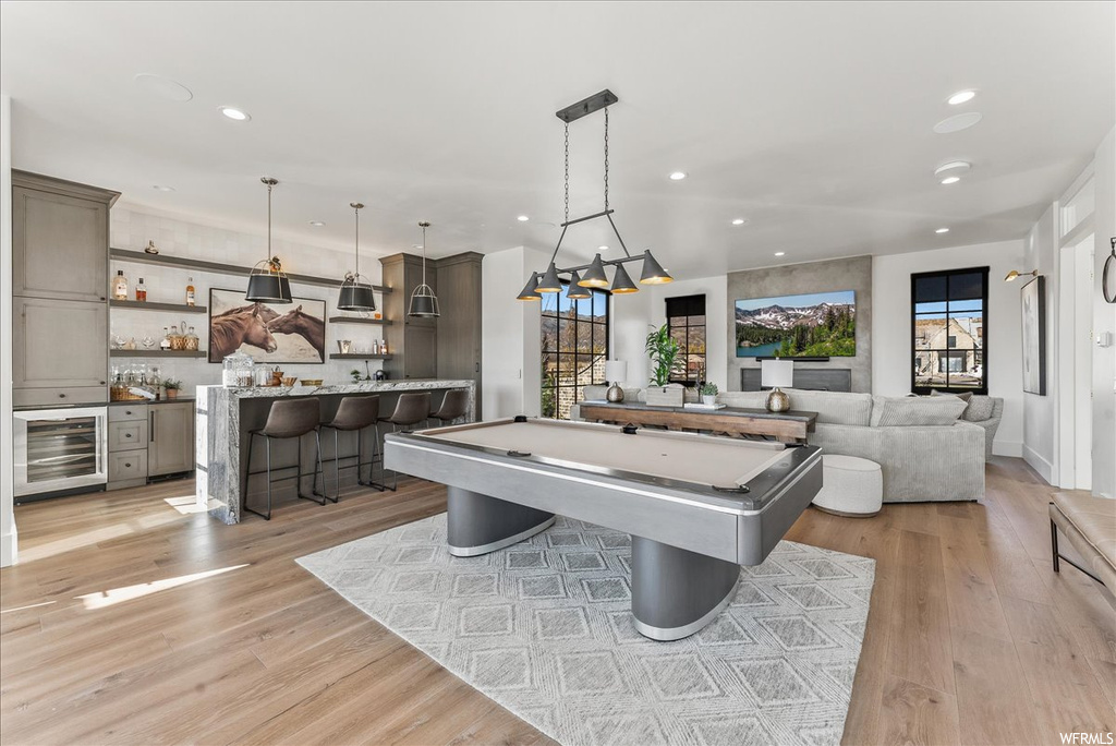Recreation room featuring billiards, light hardwood / wood-style floors, a wealth of natural light, and wine cooler