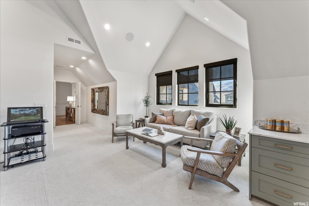 Carpeted living room featuring high vaulted ceiling