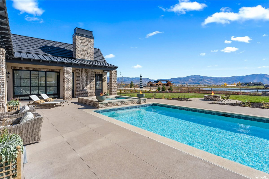 View of swimming pool with a mountain view, an in ground hot tub, and a patio