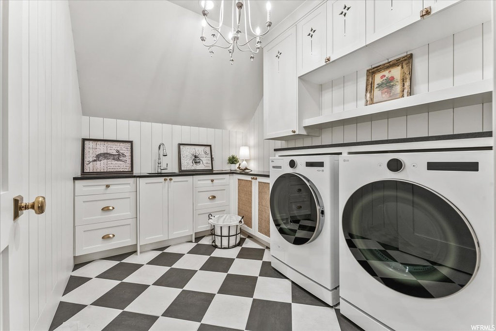 Laundry area featuring sink, light tile floors, separate washer and dryer, a notable chandelier, and cabinets