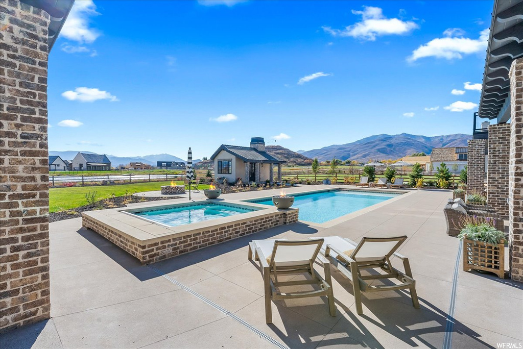View of pool featuring a mountain view, a patio area, and an in ground hot tub
