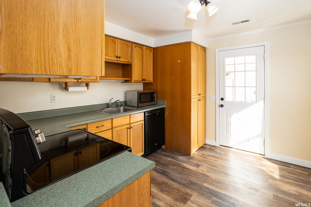 Kitchen with sink, black dishwasher, range, crown molding, and dark hardwood / wood-style flooring