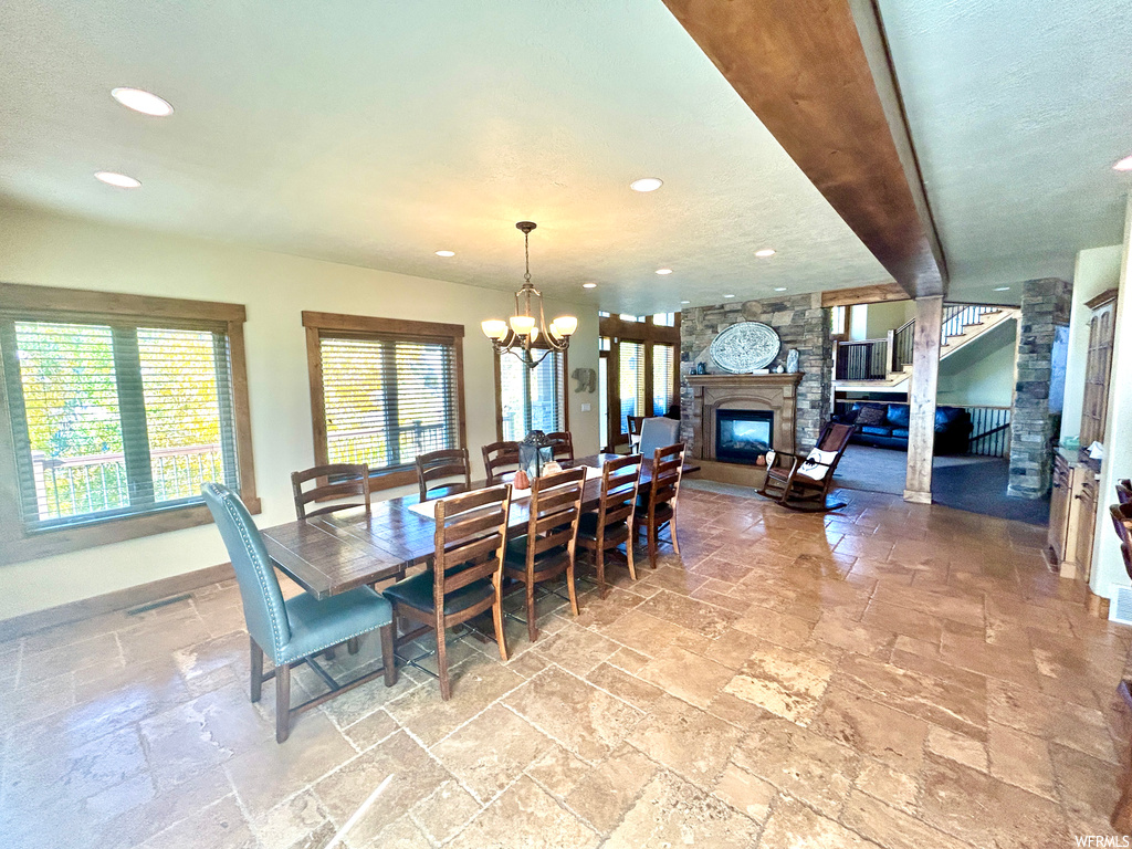 Dining area with light tile flooring, a textured ceiling, an inviting chandelier, and a fireplace