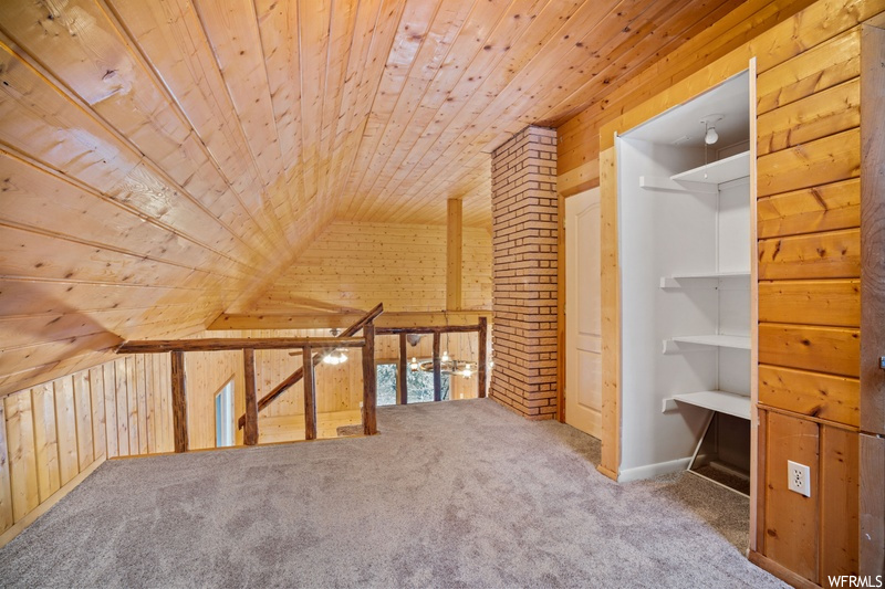 Additional living space featuring light carpet, wooden walls, brick wall, vaulted ceiling, and wooden ceiling