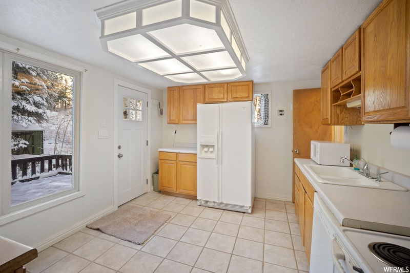 Kitchen with light tile flooring, white appliances, and sink