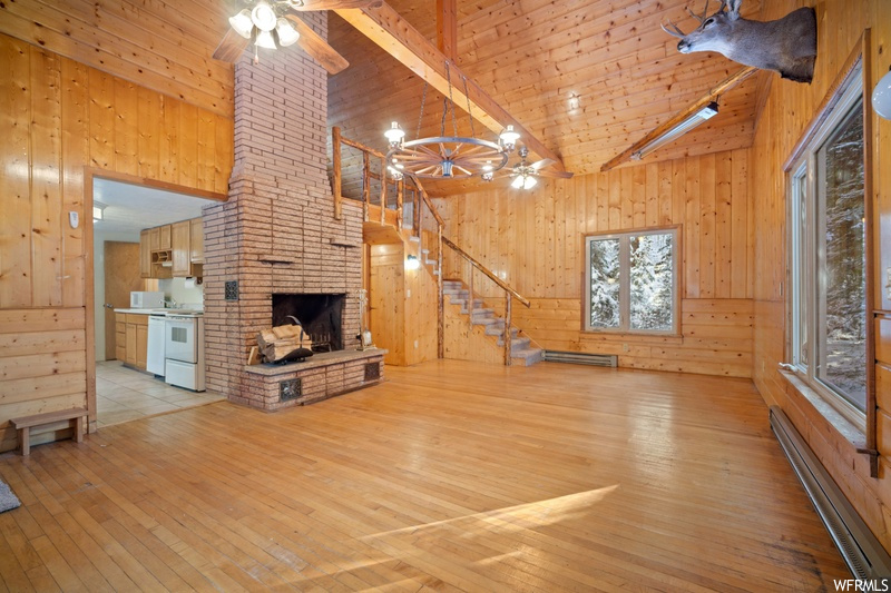 Unfurnished living room featuring wood walls, light wood-type flooring, and a fireplace