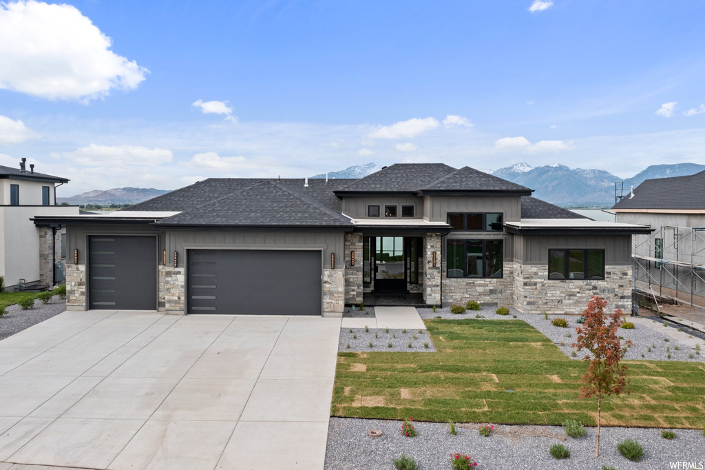 Prairie-style house with a front lawn, a mountain view, and a garage