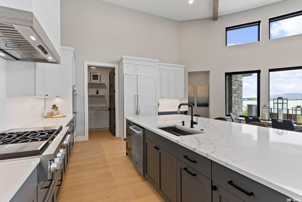 Kitchen featuring a healthy amount of sunlight, backsplash, wall chimney exhaust hood, and sink