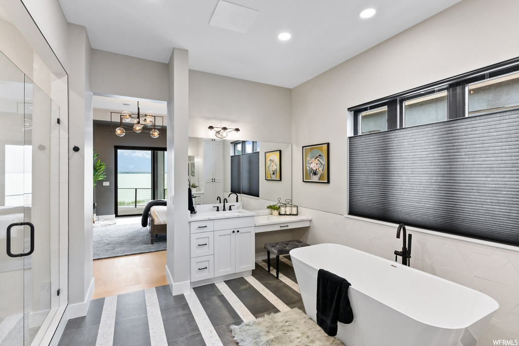 Bathroom featuring an inviting chandelier, large vanity, hardwood / wood-style flooring, and plus walk in shower